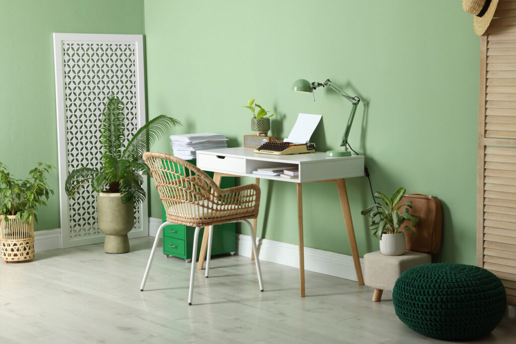 Writer’s workplace with typewriter on wooden desk near pale green wall in room